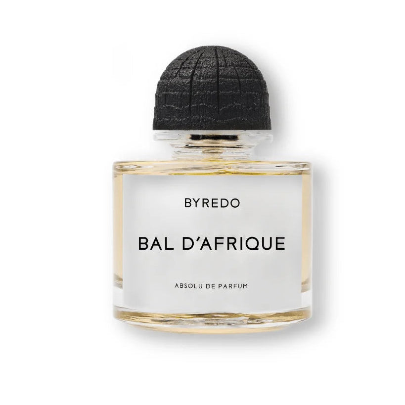 A bottle of BYREDO Bal D'Afrique perfume with a clear glass body, pale yellow liquid, a white label with black text, and a textured black cap, centered on a white background.